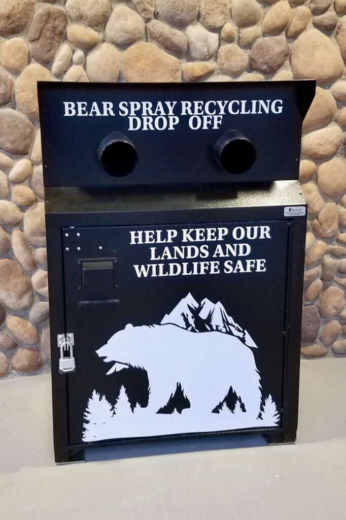 A black box with a white bear is the outside of the bear spray recycling drop off box.